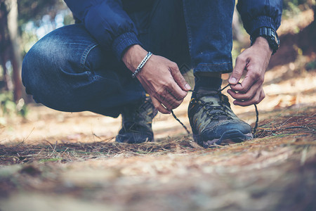 自然绿色年轻远足者在度假后将鞋带系在上年轻远足者在森林中放假背包时将鞋带系在上背部图片