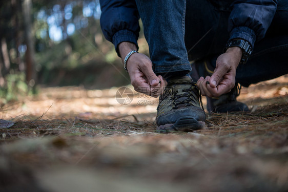 步行勘探年轻登山男子在森林中放假背包时将鞋上的带系年轻登山男子在度假后把鞋上的带绑冒险图片