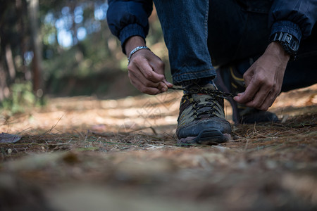 搭售树叶冒险年轻登山男子在森林中放假背包时将鞋上的带系年轻登山男子在度假后把鞋上的带绑图片