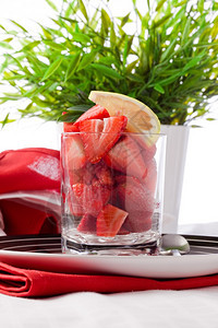 玻璃花瓣甜的草莓沙拉和白底柠檬切片照图片