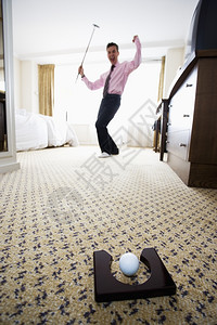 商人在酒店房间打高尔夫球时推杆玩图片