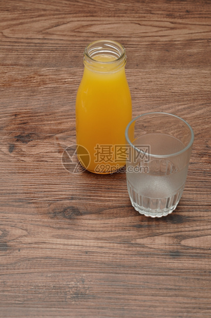 水果瓶装橙汁空杯子用木制背景隔绝传统的瓶子图片