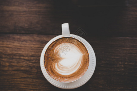 木制的陈年拿铁艺术咖啡的顶端视图木制成心形旧拿铁艺术咖啡的顶端视图木制桌子上的心脏形状卡布奇诺牛奶图片