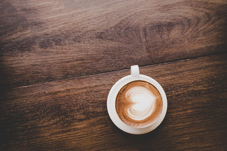 优质的食物陈年拿铁艺术咖啡的顶端视图木制成心形旧拿铁艺术咖啡的顶端视图木制桌子上的心脏形状店铺图片