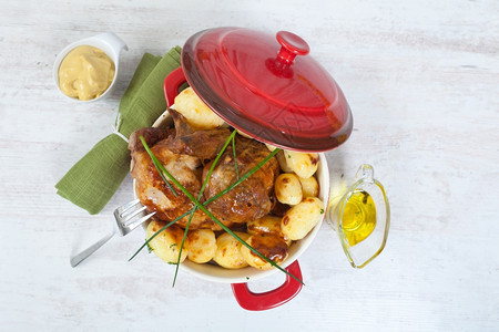 锅红色的美味鸡肉和烤土豆晚餐图片