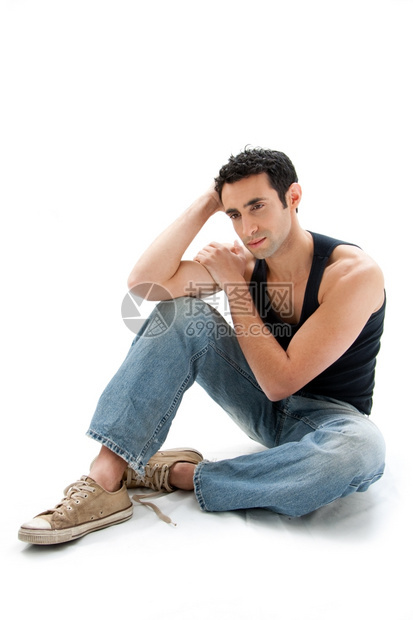 可爱的英俊穿着黑顶和牛仔裤的白人帅哥坐在地上思考与世隔绝感的图片