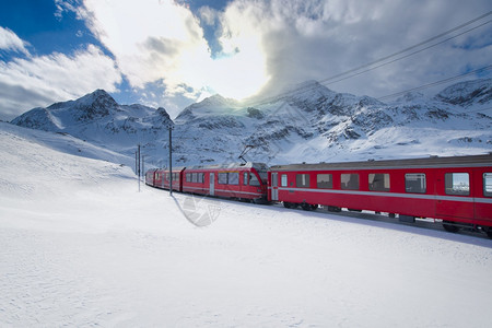 冬天红色的运输瑞士山火车BerninaExpress穿过高山雪越了伯尔尼纳快车图片
