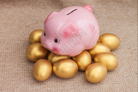 春天闪亮的粉红小猪银行爬上一堆黄麻袋金色的东面鸡蛋图片