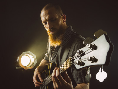 音乐家照片一名胡子男在聚光灯前的舞台上弹贝斯吉他音乐颜色图片