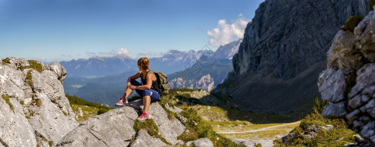 女人坐在一个小山丘上在美丽的山地风景中观登山者女士图片