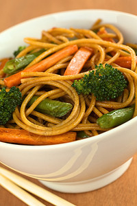 蔬菜和全麦意大利面条在白碗里用筷子烤炒薯有选择的焦点注重右边的西菜花生有蔬的PastaStirFry晚餐绿色一顿饭图片