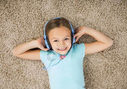 躺在地垫上戴着耳机的可爱小女孩图片