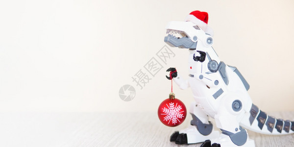 玩具机器人恐龙在圣塔帽上蜜蜂背景复制空间上有一个滚珠球胶水有创造力的圣诞老人图片