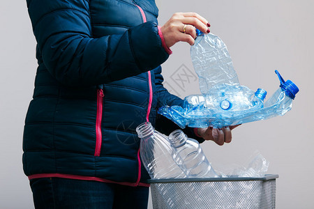环境包裹收集蓝色塑料袋废物中的空压碎瓶子以回收塑料污染概念和废物过多的概念在垃圾桶中丢弃废旧塑料瓶和包装物的妇女扔弃废旧塑料瓶和图片