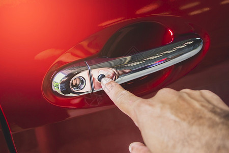 人类车辆锁孔手按着红色汽车门把手上的无键输入按钮用人手住图片
