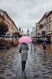 阴雨沉的秋日拿着粉色雨伞的女人在市中心散步的背影阴雨沉的秋天拿着粉色雨伞的女人在市中心散步一种粉色的落下图片