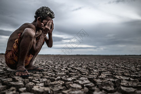 全球的裸露男人一位老坐在干燥的地上跪双手闭脸全球变暖图片