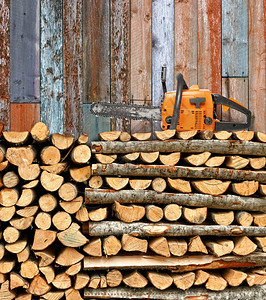 贮存细节桦木堆积的柴和链锯以挡风化的木墙图片
