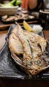 在日本的izakaya风格餐厅在金属盘上烧烤时被鱼喂养热炒食物图片