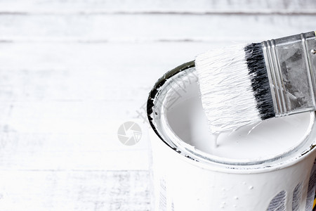 艺术的木头液体油漆刷子被浸在放白木地板上的油漆罐头中图片