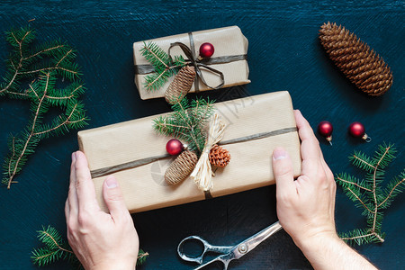 十二月枝条庆祝包装圣诞礼物裹在纸上装饰的礼品面贴着圆锥和松树枝放在木制桌子上图片