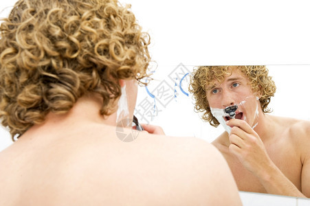年轻男人在镜子前剃脸毛刀年轻的一种图片