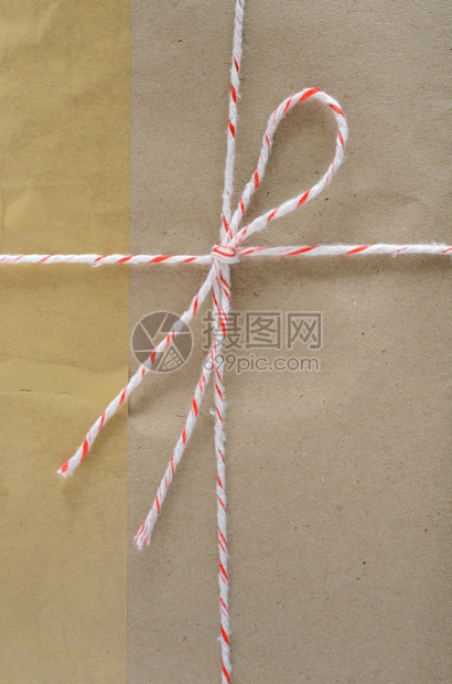 纸空白的棕色邮包裹装的递送与白色背景上的字符串和粘附胶带捆绑在一起工艺图片