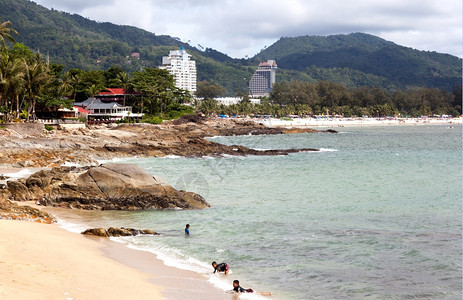芭东人们旅行泰国儿童在野生海滩游泳在背景巴东海滩和现代酒店中只有编辑图片