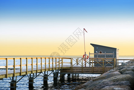 木头栏杆在瑞典南海岸一个宁静的夜晚生命保护站和码头朝达内马克方向看去晚上图片