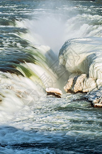 雪一种冰岛西南部Urridafos瀑布的紧靠在阳光明媚的天候下冰岛Urridafos瀑布岩石图片