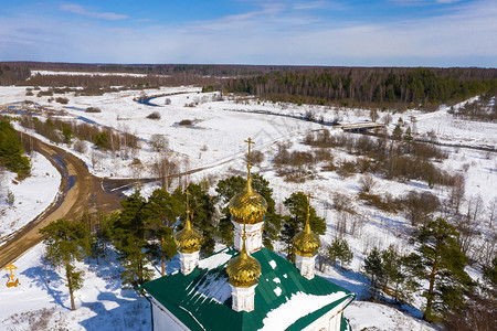蓝色的伊凡诺沃地区Stromikhino村基督复活教堂金色圆顶在阳光明媚的一天以雪田和森林为背景云一种图片