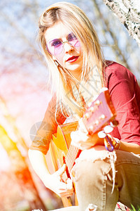 金发女孩在春天的户外弹吉他草地头发女图片
