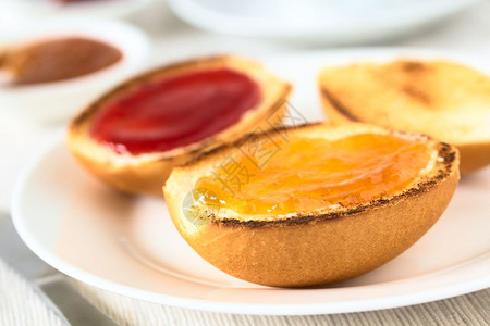 非洲大陆早餐包括加黄油桃子和草莓果酱的烤面包卷以自然光显示选择焦点在第一个面包卷大陆早餐中关注桃果酱前方第一张面包卷大陆早餐重点图片