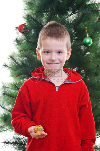 孩子微笑年轻男的肖像拿着小礼物盒站在圣诞树前看着摄像机笑声在室内图片