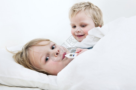 明亮的关怀生病年轻男孩用温度计测量床上发烧情况而他的弟却想让开心起来笑声羽绒被图片