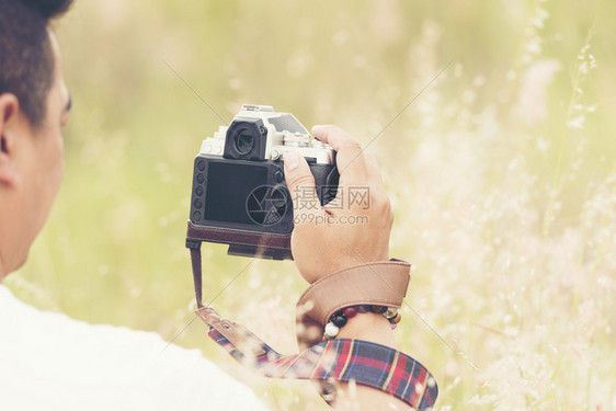 数字的潮人专业摄影机在手里握着草地年轻的图片