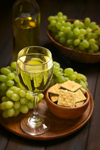 酒精盘子自然白葡萄饼干和一瓶酒的白葡萄杯用天然光聚焦点在暗木上拍照重点放在葡萄酒杯前端以红酒杯为焦点图片