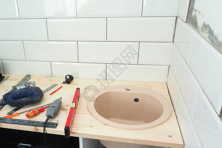 洗涤在厨房安装木制柜台在厨房墙上部分铺设陶瓷砖修理工具使用白色的铅笔图片