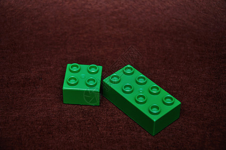不同的棕色背景上两个不同大小的绿色建筑构件塑料教育图片