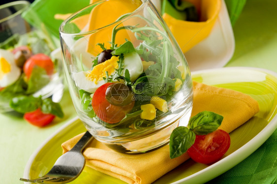 厨房餐厅盘子绿色木制餐桌上杯子里混合沙拉的美味开胃菜图片