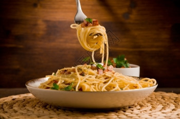 美味的意大利面配培根和鸡蛋木桌上叫阿拉卡马巴木制的美食图片