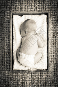 孩子新生婴儿睡在用白布装有的旧木箱内睡眠图片