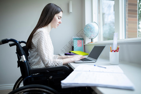 在家工作室内疾病家用笔记本电脑学习的轮椅女青少年图片