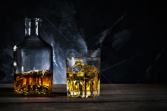朗姆酒摇篮和一杯威士忌配有冰的木制餐桌摇椅和杯威士忌加冰滗水器黑暗的图片