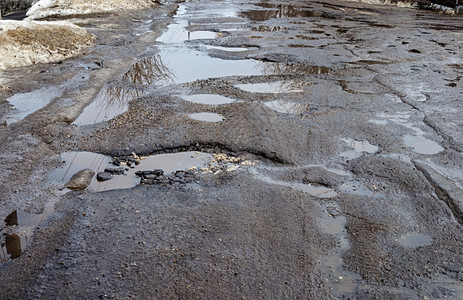 农村春天有大坑洞和泥水的公路阳光明媚的春日图片