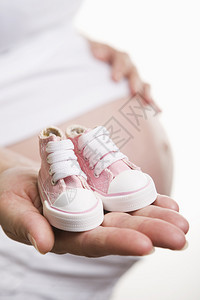 孕妇为女婴穿着粉红鞋的孕妇腹部婴儿母亲图片