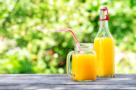 瓶子和罐木板上含橙汁的罐子绿色天然背景夏仍活着瓶子和罐木桌上含橙汁的罐子食物自然生活图片