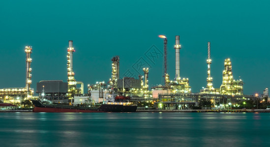 绿色背景照亮的炼油厂工蓝色的塔夜晚图片