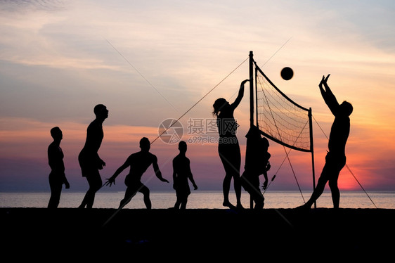 夕阳下在沙滩边打排球的人们图片