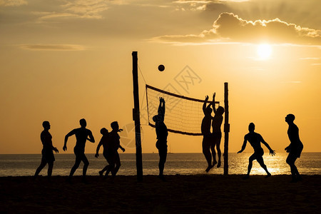 夕阳下在沙滩边打排球的人们海滩上和日落的操场沙子夏天玩日出图片